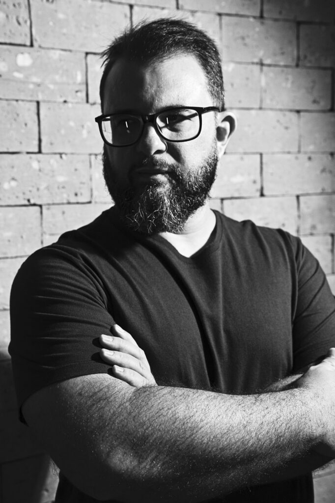 Black-and-white portrait of Rodolfo Mendes with arms crossed, looking past the camera.